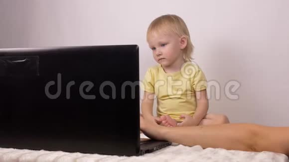 妈妈在她小女儿的笔记本电脑上放了卡通片小女孩看着笔记本电脑视频的预览图