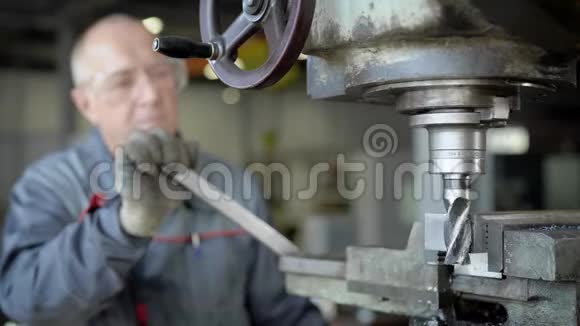 老主人在工厂的一个车间工作控制钻床加工金属细节视频的预览图