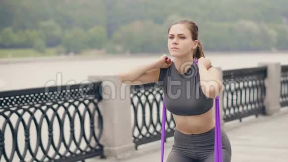 健身妇女使用运动扩张器蹲在户外健身训练视频的预览图