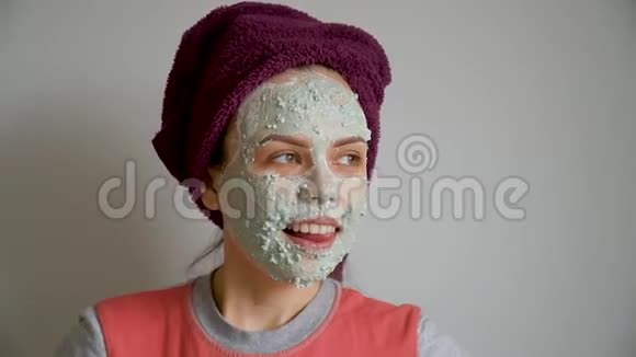 从面部皮肤上去除化妆品绿色去皮面膜的美丽女孩肖像视频的预览图