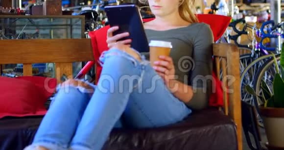 在第4k车间使用数码平板电脑时喝冷咖啡的妇女视频的预览图