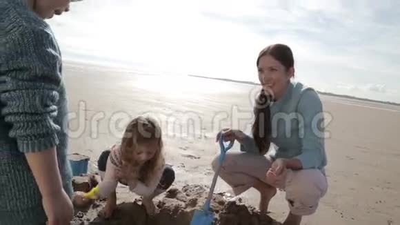 妈妈和孩子们一起在海滩上挖掘视频的预览图