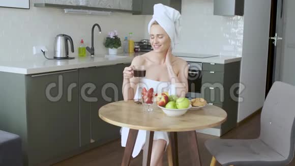 美丽的女人头上戴着毛巾吃着健康的早餐和咖啡视频的预览图