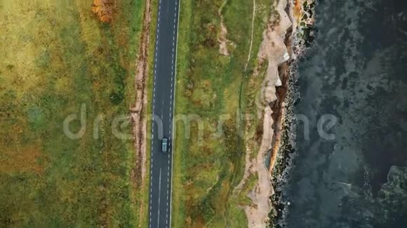 俯视空中跟踪拍摄的黑色汽车沿着大气秋海岸公路行驶美丽的侵蚀海岸视频的预览图
