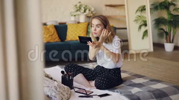 迷人的年轻女士正在画眉毛早上化妆坐在现代公寓的床上化妆品视频的预览图