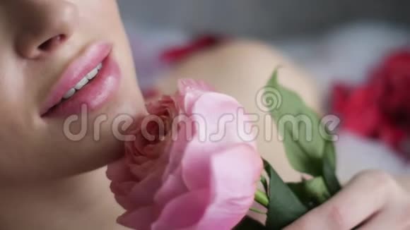 一个女人躺在浴室里手里拿着一朵粉红色的玫瑰视频的预览图