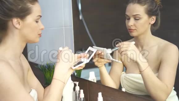 在浴室镜子前化妆的漂亮女人视频的预览图