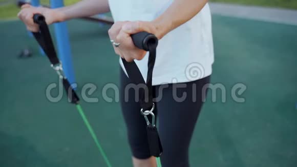 一个女孩在街上用橡胶扩张器训练力量训练视频的预览图