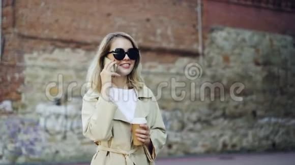 金发美女在城市里边走边打手机边喝外卖咖啡视频的预览图