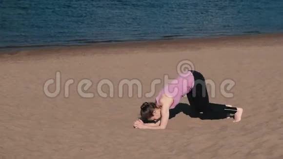 女人在城市河边的海滩上做瑜伽美丽的景色倒立空中的嫩枝视频的预览图