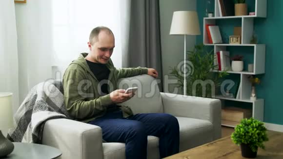 一对年轻夫妇在舒适的客厅里用智能手机看有趣的视频视频的预览图