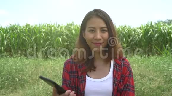 开朗的亚洲女农民和企业家摆姿势在玉米作物和微笑使用手机视频的预览图