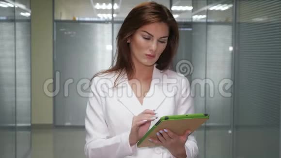 戴着平板电脑的红发女商人站在办公室走廊视频的预览图