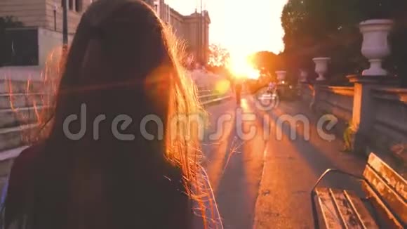 年轻的金发少女在惊人的日落中行走美丽少女游客走下路后景温暖的灯光视频的预览图
