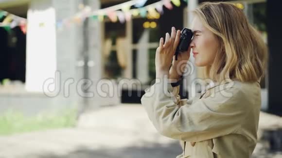 迷人的年轻女摄影师用现代相机在夏天的美丽城市户外拍照视频的预览图