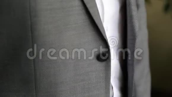 新郎在扣一件夹克穿西装的时髦男人把扣子系在夹克上准备出门视频的预览图