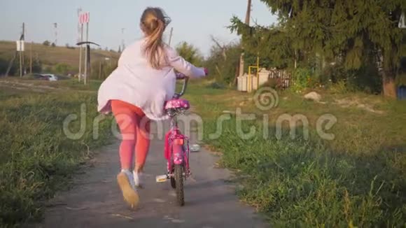女孩青少年在夏天骑自行车在城市日落视频的预览图