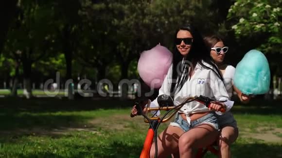 两个穿着短牛仔短裤和白色t恤的黑发小女孩骑着电动摩托车视频的预览图