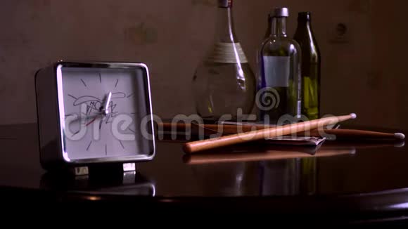 在一张光滑的棕色木桌上有一个反光有一个白色表盘一个钟和鼓棒的方形银视频的预览图
