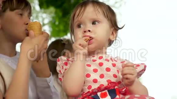 小女孩正和家人坐在公园的长凳上吃冰淇淋视频的预览图