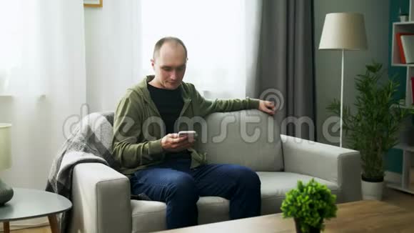 一对年轻夫妇在舒适的客厅里用智能手机看有趣的视频视频的预览图