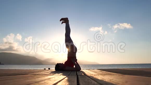 4k女性剪影日出时在海边慢动作做瑜伽视频的预览图
