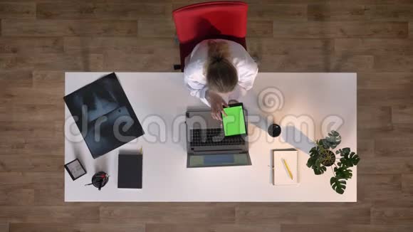 年轻的医生穿着白大褂带有色度的平板电脑上打字医学概念顶部拍摄坐在桌子上用x射线扫描视频的预览图