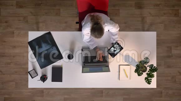 年轻的女医生拿着X光图像的药片喝着咖啡上面的照片坐在桌子旁医学概念视频的预览图