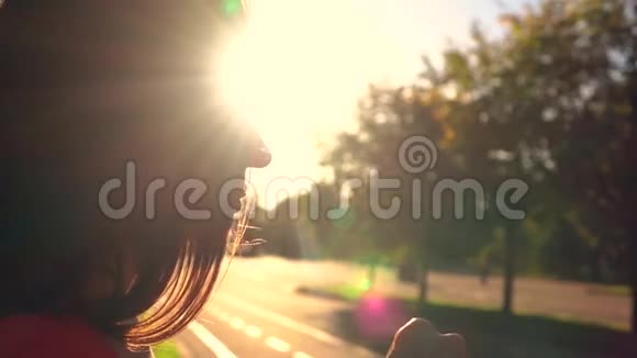 美丽的黑发女孩在公园里从塑料瓶里喝水温暖的夕阳颜色慢镜头视频的预览图