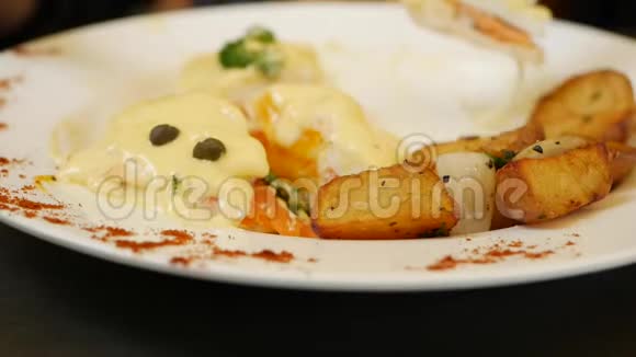 女人拿着刀叉吃鸡蛋本尼迪克特鸡蛋本尼迪克特面包番茄和乡村烤土豆视频的预览图