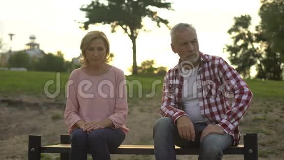 一对老夫妇坐在长凳上悲伤的男人看着他心烦意乱的妻子争吵着视频的预览图