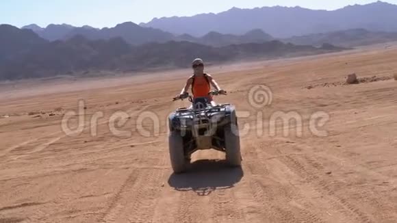 在埃及沙漠山脉的背景下骑着四方自行车的性感女孩骑着它慢动作视频的预览图