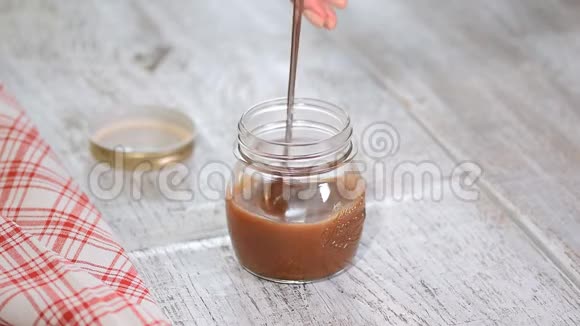 自制咸焦糖酱在罐子里的乡村木桌背景视频的预览图