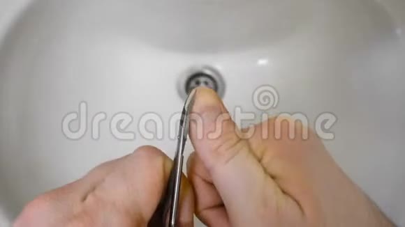早晨时间流逝的人用剪刀在浴室的水槽上剪指甲视频的预览图