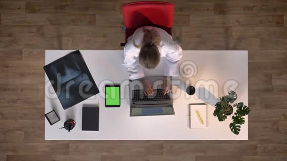 年轻的护士在笔记本电脑和带有色度的平板电脑上打字坐在桌子上用x光扫描医学概念顶级照片视频的预览图