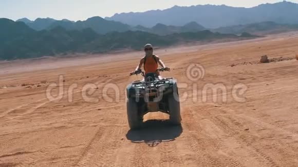 在埃及沙漠山脉的背景下骑着四方自行车的性感女孩骑着它慢动作视频的预览图