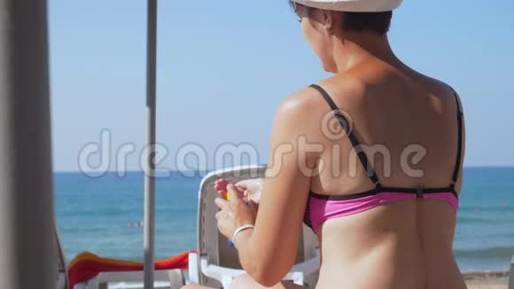 女孩在海滩上把奶油涂在肩膀上视频的预览图