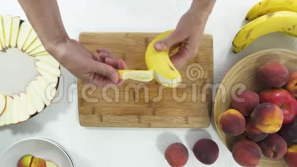 香蕉切片在木制砧板上女人剥皮和切片香蕉视频的预览图