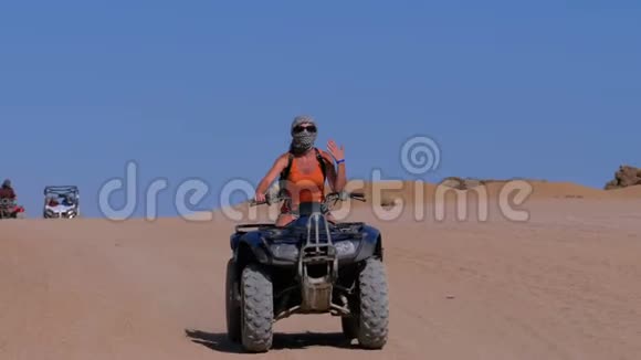 一个骑四方自行车的女孩在埃及沙漠山脉的背景下骑着自行车慢动作视频的预览图