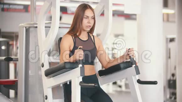 一名运动员女子在健身房训练表演一个腿部运动训练装置视频的预览图