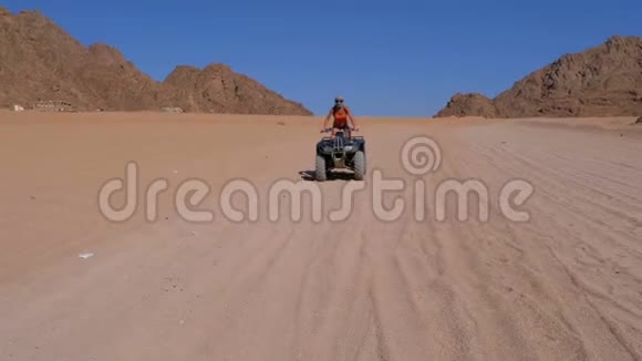 一个骑四方自行车的女孩在埃及沙漠山脉的背景下骑着自行车慢动作视频的预览图
