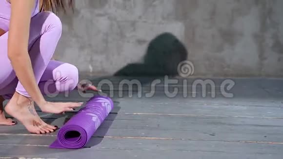 年轻女子打开一张垫子在工作室练习瑜伽视频的预览图
