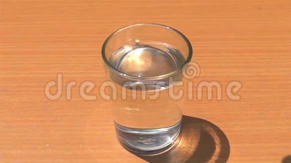 把自制的冰块放入盛有淡水的玻璃杯中放在木桌上视频的预览图