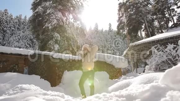 穿着针织毛衣和毛皮帽的漂亮女孩在Chalet附近享受阳光明媚的冬日视频的预览图