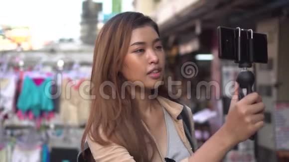 年轻的女游客拿着带智能手机和录音录像的万向节旅游博客和vlogge视频的预览图