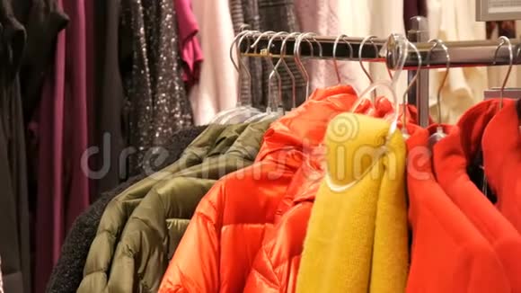 在商场或购物中心的一家服装店里各种颜色的暖身女人衣服挂在衣架上视频的预览图