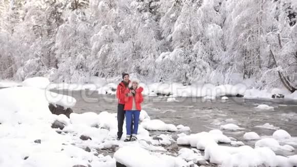 恋爱中的情侣在冬天的河岸边玩得开心欣赏冬天的大自然视频的预览图