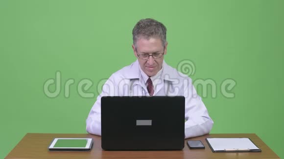 成熟男医生多任务工作靠木桌的画像视频的预览图
