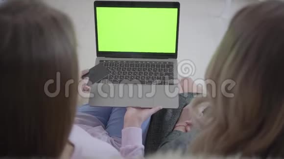 两个女孩正在笔记本电脑上通过绿色屏幕上网寻找优惠折扣视频的预览图