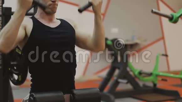 一个穿着黑色T恤的肌肉男正在健身俱乐部的健身机上训练视频的预览图